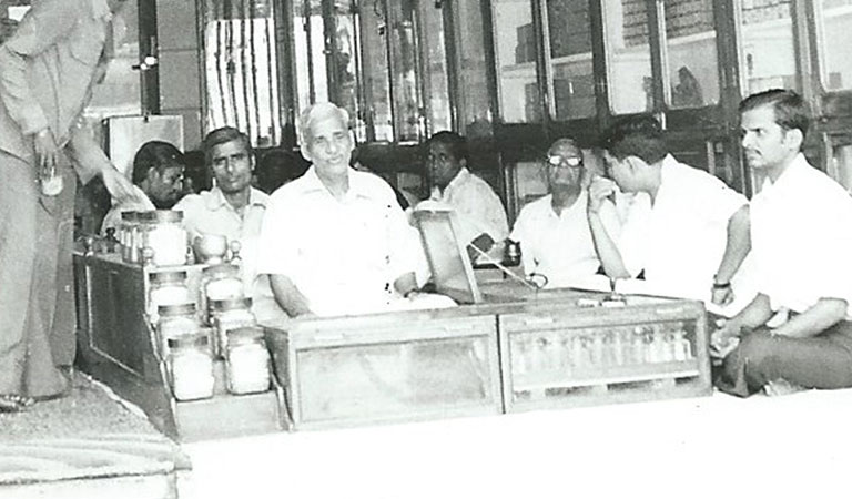 Black and white image of a man selling spices in sho