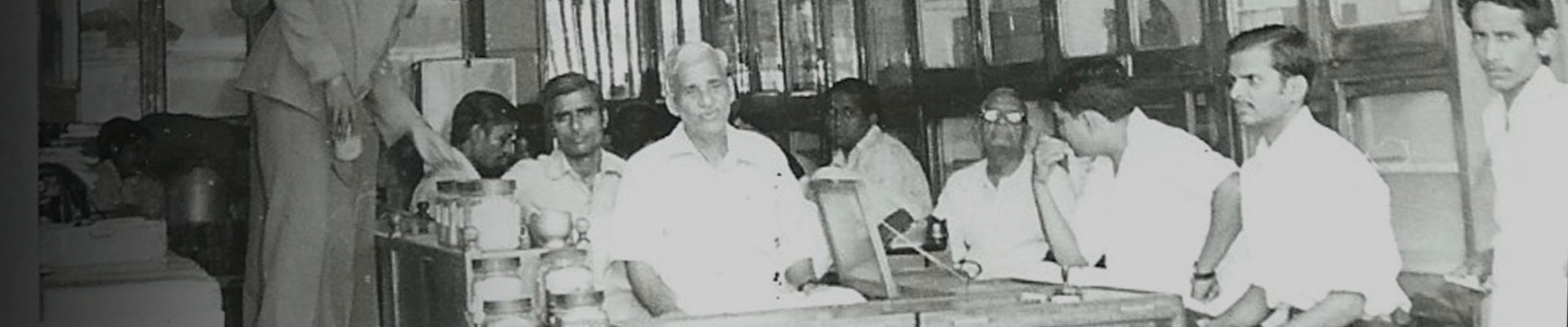 Black and white image of a man selling spices in sho